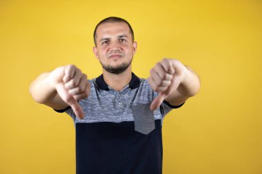 İzole edilmiş sarı arka planda duran Rus adam mutsuz ve kızgın görünüyor. Reddedilmiş ve olumsuz bir hareket sergiliyor. Kötü ifade