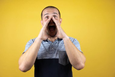 Sarı arka planda dikilen Rus adam el pençe divan durup el pençe çığlıklar atıyordu. İletişim konsepti.