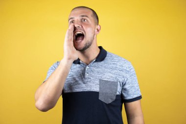 Rus adam sarı arka planda durmuş el ele tutuşarak bağırıyor ve çığlık atıyordu. İletişim konsepti.
