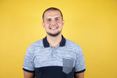 Yüzünde mutlu ve serin bir gülümsemeyle, izole edilmiş sarı arka planda duran Rus bir adam. Şanslı kişi..