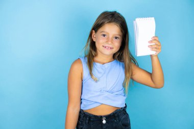 Güzel bir kız çocuğu, izole edilmiş mavi arka planda gülümsüyor. Pençe hareketlerini kedi gibi yapıyor, agresif bir ifade.