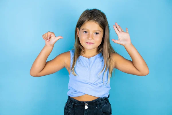 年轻美丽的小女孩 在孤独的蓝色背景上 带着自信和快乐的微笑 用手指指指着六号 — 图库照片