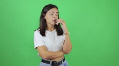 Genç, güzel bir kadın yeşil arka planda çaresiz ve endişeli yürüyor.