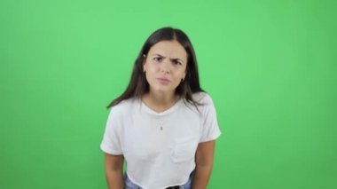 İzole edilmiş yeşil arka planda genç ve güzel bir kadın ekranı işaret ediyor ve el sallıyor.