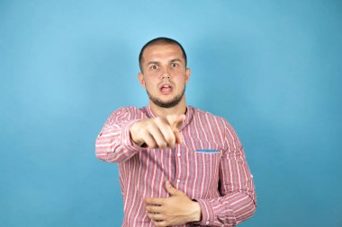 Rus iş adamı kırmızı gömlekli, mavi arka planda parmağı önde, ağzı açık, şaşırmış, ön tarafta bir şey var.