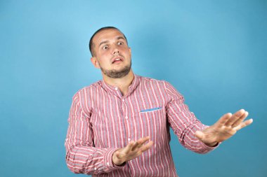 Rus iş adamı mavi arka planda korkmuş ve korkudan dehşete düşmüş. El hareketlerini durdur, şok içinde bağır. Panik konsepti.