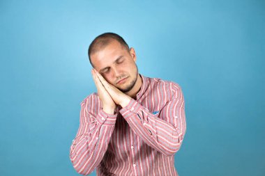 Mavi arka planda uyuyan Rus iş adamı yorgun düşler görüyor ve elleri ile poz verirken kapalı gözlerle gülümsüyor..