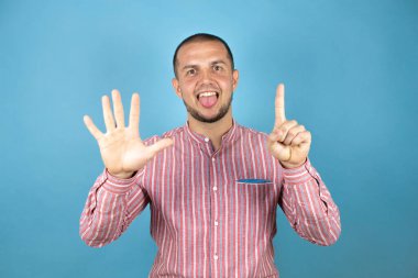 Rus iş adamı mavi arka planda kırmızı bir gömlek giyiyor. Altıncı parmaklarını gösterip işaret ederken kendinden emin ve mutlu gülümsüyor..