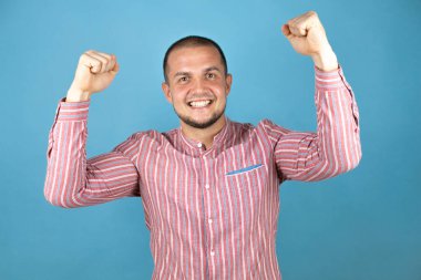 Rus iş adamı mavi arka planda gururla gülümseyen kol kaslarını gösteriyor