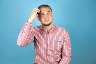 Mavi arka planda Rus bir iş adamı bir elini kafasına koyup sanki bir şey unutmuş gibi gülümsüyordu.