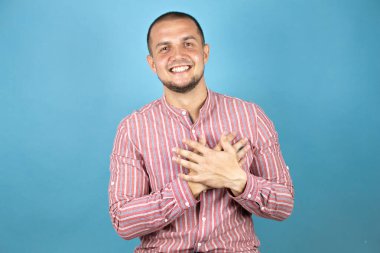 Mavi arka planda, elleri göğsünde gülümseyen ve yüzünde minnet ifadesi olan bir Rus iş adamı..