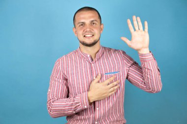 Mavi arka planda gülümseyen, elleri göğsünde ve parmakları havada yemin eden, sadakat yemini eden bir Rus iş adamı.