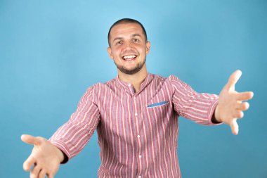 Rus iş adamı mavi arka planda kameraya bakıyor. Sarılmak için kollarını açmış gülümsüyor..