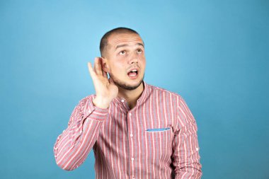 Mavi arka planda sırıtan bir Rus işadamı. Kulağı kulağında bir söylenti ya da dedikoduyu dinliyor.