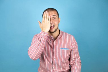 Rus iş adamı mavi arka planda bir gözünü eliyle kapatıyor, yüzünde kendine güvenen bir gülümseme ve şaşırtıcı bir duygu var..