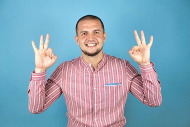 Rus iş adamı mavi arka planda olumlu bir şekilde iki elinle ve parmaklarınla imza atıyorsun. Başarılı ifade