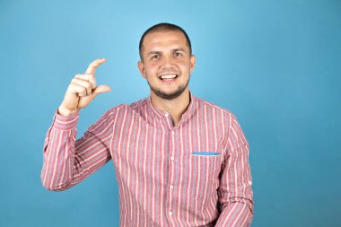 Rus iş adamı mavi arka planda, elleri küçük boyda, parmaklarıyla işaret veriyor ve kamera var..