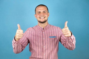 Rus iş adamı mavi arka planda elleriyle sinyal veriyor. Kameraya bakıp başarıyı gösteren ifade onaylanıyor