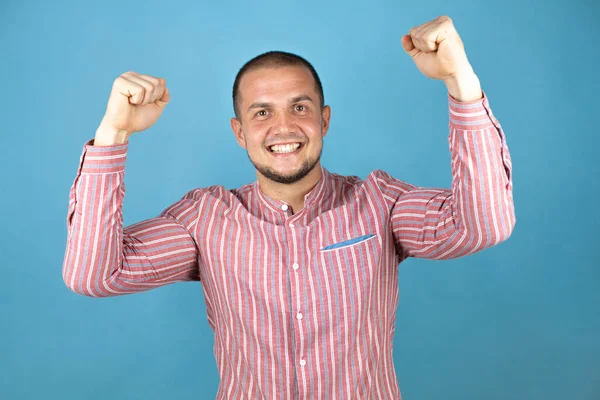 Rus iş adamı mavi arka planda gururla gülümseyen kol kaslarını gösteriyor