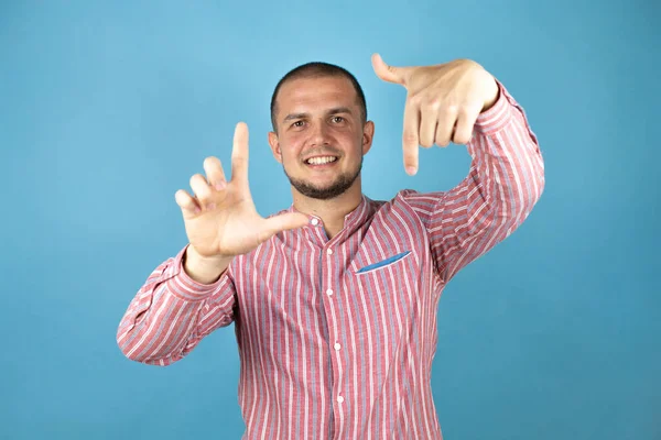 Rus iş adamı mavi arka plan üzerinde el ve parmakları kullanarak çerçeve yapıyor, kamera perspektifi