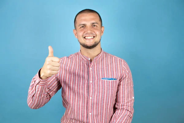 Rus iş adamı mavi arka planda mutlu bir el hareketi yapıyor. Kameraya bakıp başarıyı gösteren ifade onaylanıyor