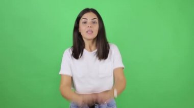 Genç ve güzel bir kadın yeşil arka planda çok mutlu ve heyecanlı kollarını kaldırarak, gülümseyerek ve başarı için bağırarak kazanan jestler yapıyor..