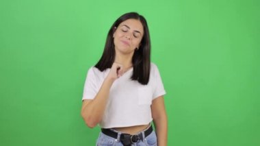 Tecrit edilmiş yeşil arka planda genç ve güzel bir kadın kendini işaret ediyor ve kendinden emin.