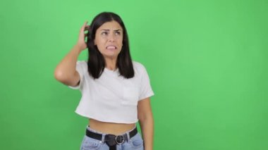 Kafası karışmış bir kız sorunu nasıl çözeceğini düşünürken kafasını kaşıyor, şaşkın ve kuşkulu bir bakışla düşünüyor. Stüdyo çekimi yeşil arkaplanda izole edildi