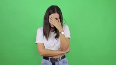 Sefil, depresif ve dramatik genç bir kadın yeşil arka planda yalnız ve güzel bir kadın ağlıyor ve gözyaşlarını siliyor, mağlubiyet mağlubiyetini yaşıyor, yalnızlık ve çaresizlik içinde acı çekiyor..