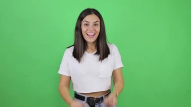 Nasıl kazanacağımı biliyorum! Tecrit edilmiş yeşil arka plan üzerinde zeki, genç ve güzel bir kadın kurnazca gülümsüyor, büyük kâr fikirlerine sahip ve para hareketi gösteriyor, parayı, vücut dilini taklit ediyor..