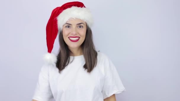 ณเล อกฉ นเหรอ สาวสวยประหลาดใจท สวมหมวกซานตาคลอส เหน นหล ขาวท โดดเด และมองในความประหลาดใจ — วีดีโอสต็อก