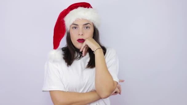 可怜而又无聊的年轻女子 戴着圣诞老人的帽子 躺在孤独的白色背景上 脸上挂着忧郁的表情 对生活不感兴趣 缺乏动力 — 图库视频影像