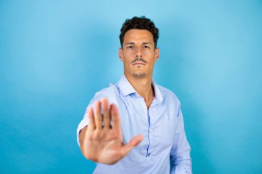 Mavi arka planda mavi gömlek giyen genç yakışıklı adam ciddi ve avucunun içi gibi şarkı söylemeyi kesiyor..