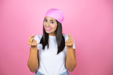 Soyutlanmış pembe arka planda pembe başörtüsü takan güzel bir kadın.