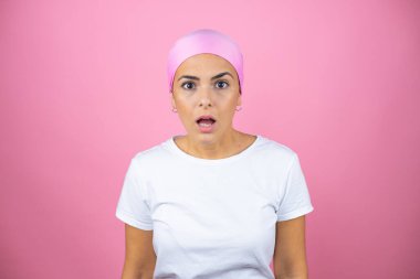 Pembe başörtüsü takan genç ve güzel bir kadın pembe arka planda korku ve şaşkınlık dolu bir ifade, korku ve heyecan dolu bir yüz..