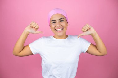Pembe başörtüsü takan genç ve güzel bir kadın pembe arka planda kendine güvenen, yüzünde bir gülümsemeyle, gururlu ve mutlu bir şekilde kendini gösteren..