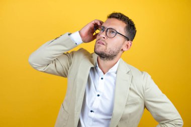 Sarı arka planda takım elbise giyen yakışıklı genç bir işadamı bir elini kızın kafasına koyup sanki bir şey unutmuş gibi gülümsüyordu.