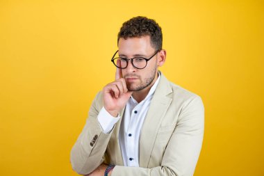 Soyutlanmış sarı arka planda takım elbiseli yakışıklı bir iş adamı.