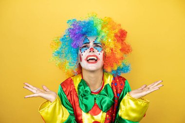 Sarı arkaplanda dikilen soytarı. Kolları ve elleri havada, kafası karışmış bir ifade.