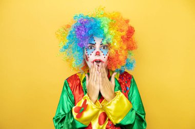 Sarı arkaplanda elleri ağzında duran palyaço şaşırdı.