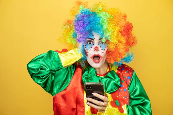 Sarı arkaplanda dikilen palyaço telefonuyla sohbet ediyor ve şaşırdı.