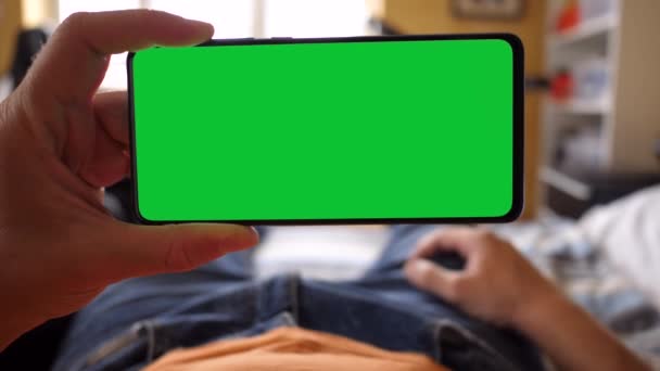 Holde en grøn skærm Smartphone mens Liggende på sengen – Stock-video