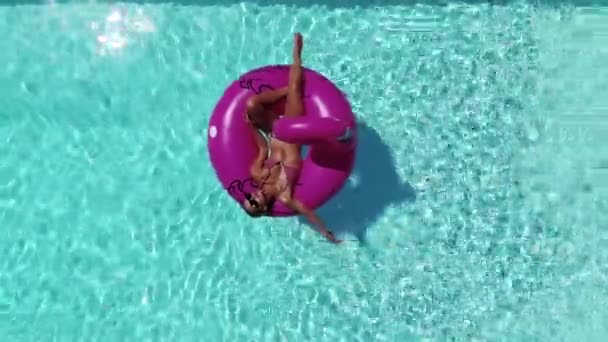 Женщина на надувном фламинго наслаждается летом у бассейна — стоковое видео