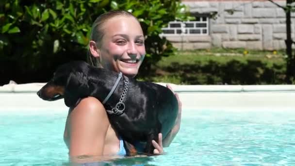 Mujer bonita sosteniendo su lindo perro salchicha en la piscina — Vídeo de stock