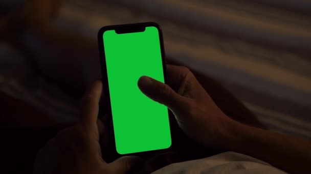 Milaan, Italië - augustus 202: Het houden van een groene scherm iPhone, Liggen op het bed bij Dusk — Stockvideo