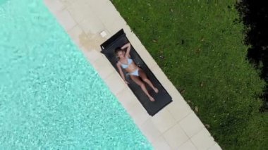 Havuzunda güneşlenen güzel bir kadın.