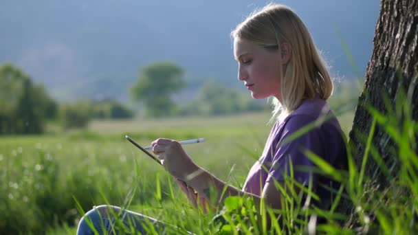 Pretty Woman skizziert mit ihrem Tablet in der Wildnis, Nahaufnahme — Stockvideo