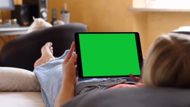 Mujer sosteniendo una tableta horizontal de pantalla verde, acostada en la cama — Vídeos de Stock