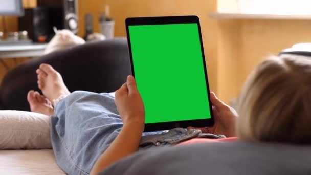 Mulher segurando um tablet de tela verde vertical, deitada na cama — Vídeo de Stock