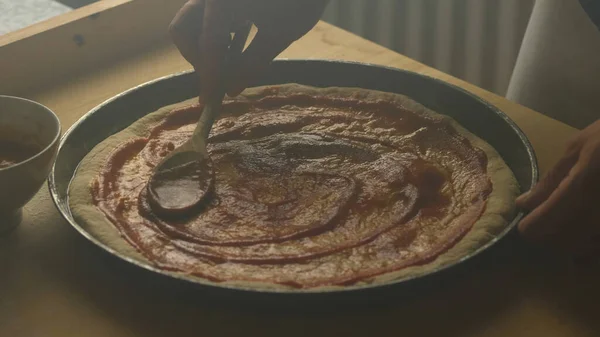 Uomo che applica salsa di pomodoro sulla pasta della pizza, cibo sano fatto in casa — Foto Stock